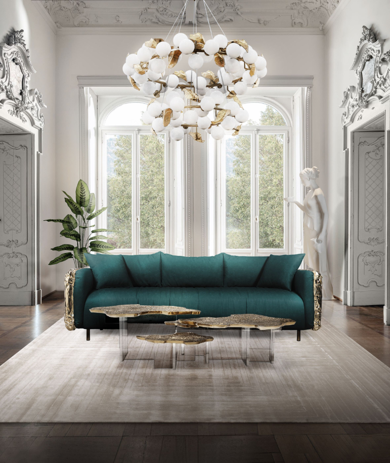 living room in neutral tones with a gold chandelier and center table, and a green sofa